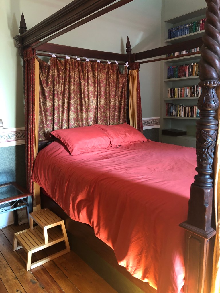 A bed with a burnt orange comforter.