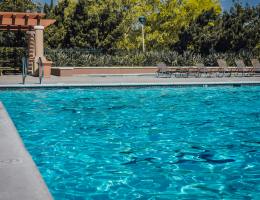 An empty pool with lounge chairs on the side.